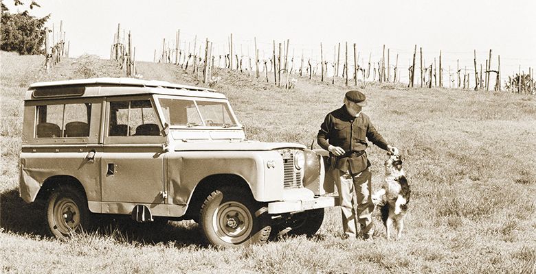 David Lett plays with his Border Collie, Tibby, next to his 1967 Land Rover 88 series in 1991 at Eyrie’s vineyard.##Photo by Tom Ballard