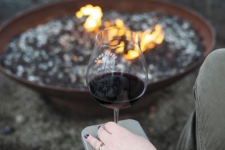 A person enjoying the fire at Abbey Road Farm while drinking a glass of red wine. ## Photo provided by Abbey Road Farm A person enjoying the fire at Abbey Road Farm while drinking a glass of red wine. ## Photo provided by Abbey Road Farm