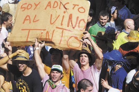 Two men in wine-stained T-shirts hold a sign in the
crowd gathered in Plaza Mayor in Aranda de Duero for the start of the Festival of the Virgin of the Vines.