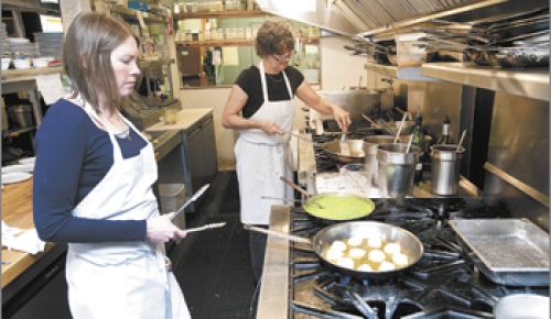 Tina’s co-owner Tina Bergen, background,
and chef Abby McManigle prepare the scallop entrée for the Dundee restaurant’s 20th
anniversary media luncheon.