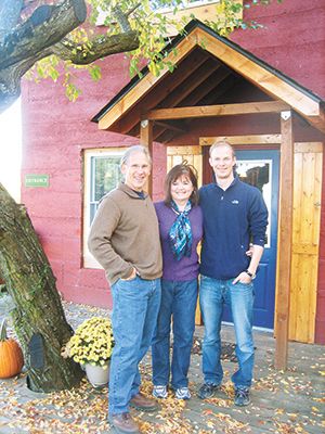 Owners Dick and Pat Ellis and their son, Teddy, stand in front Pebblestone Cellar’s tasting room, a charming 1906 hand-poured concrete cottage. ##Photo provided.