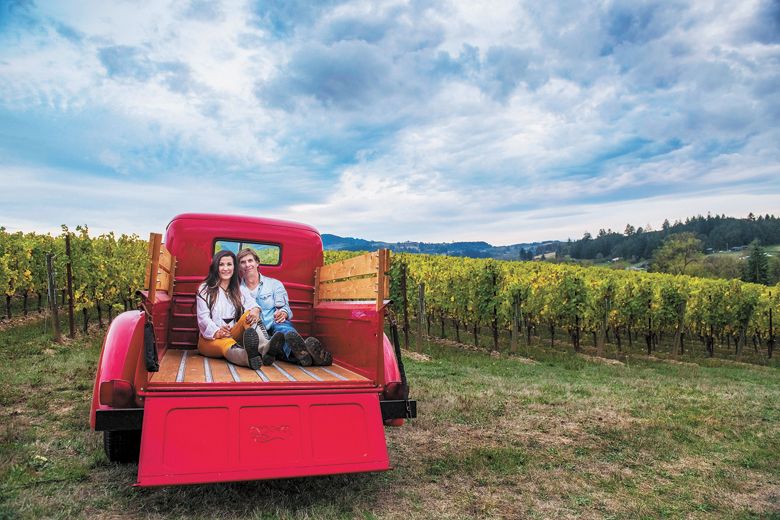 Anacréon Winery owners, Danell and Kipp Myers, enjoy time in their Chehalem Mountains estate vineyard.  Their red 1947 Ford pickup is the winery mascot, perfect for photos and enjoyed by visiting guests. ##Photo BY CAROLYN WELLS KRAMER