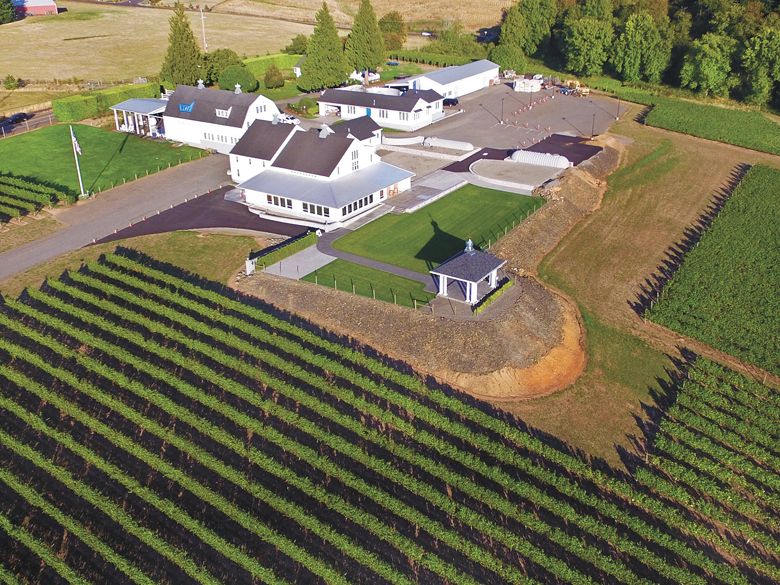 Aerial view of the winery grounds with several restored white barns, surrounded by vineyards.##Photo by Aniko Photography Aerial view of the winery grounds with several restored white barns, surrounded by vineyards.##Photo by Aniko Photography