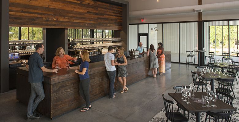 The long bar inside the tasting house allows more guests to sample wine than the previous farmhouse space allowed.##Photo by Andrea Johnson