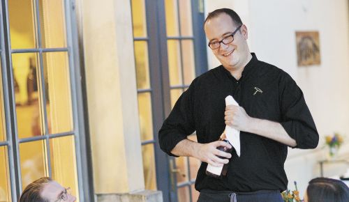 Christopher Berry, The Dundee Bistro’s sommelier, opens a bottle at one of the many al fresco tables. The wine list offers many Oregon selections and some international, too. ##Photo by John Valls.