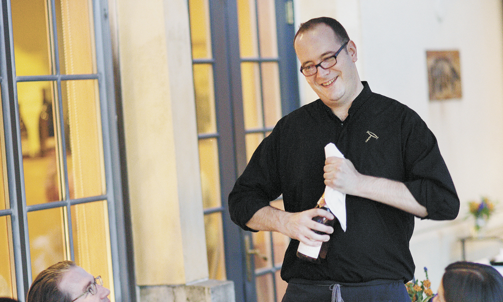 Christopher Berry, The Dundee Bistro’s sommelier, opens a bottle at one of the many al fresco tables. The wine list offers many Oregon selections and some international, too. ##Photo by John Valls.