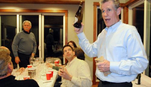 At one of his monthly blind tastings, Peter Adesman reveals a wine to his fellow oenophiles, including Ron Rezek (standing) and Paul
Jorizzo (sitting).