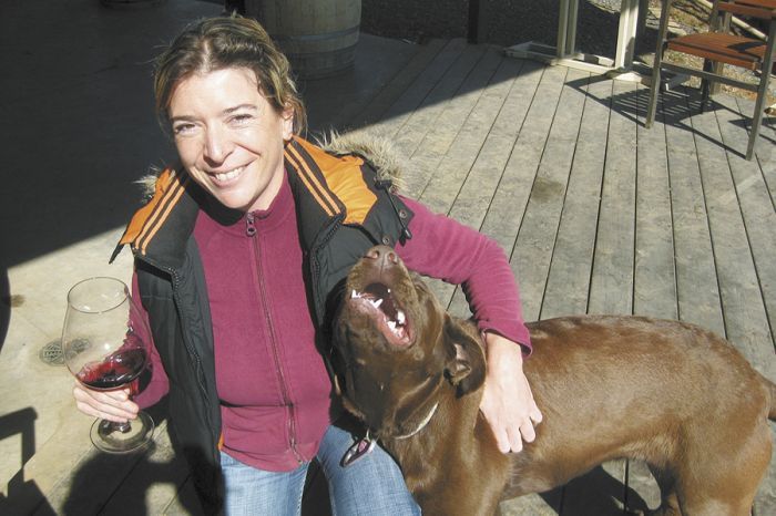 Alexandrine Roy enjoys a glass of wine and the Phelps Creek vineyard puppy, Rosie Rosé, a nine-month-old chocolate Labrador Retriever.