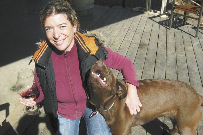 Alexandrine Roy enjoys a glass of wine and the Phelps Creek vineyard puppy, Rosie Rosé, a 9-month-old chocolate Labrador Retriever.