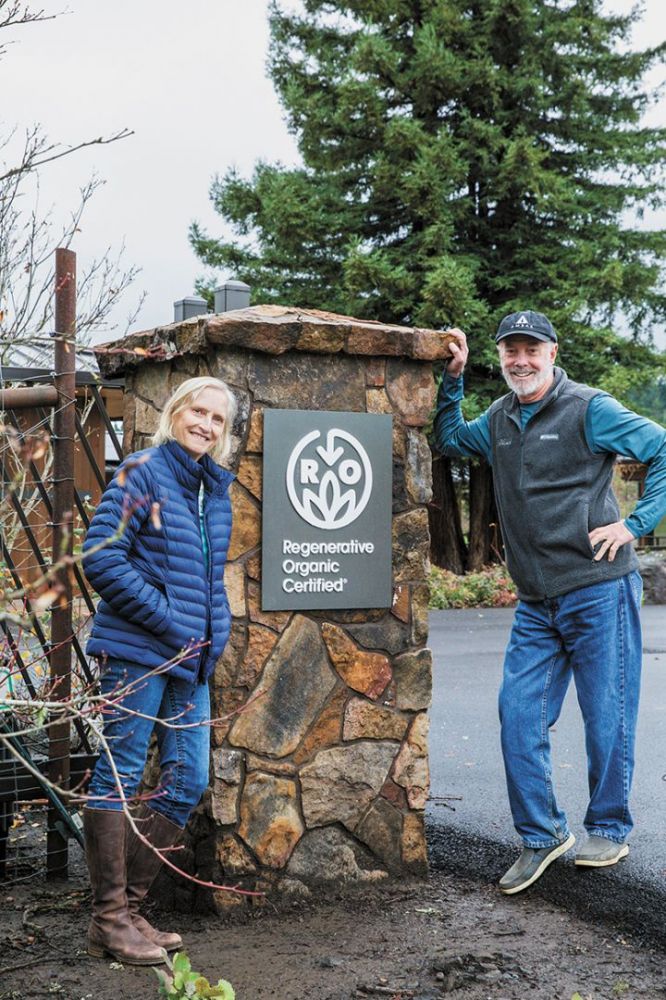 Ambar Estate owners Pam Turner (left) and Rob Townsend, posing with the winery&rsquo;s Regenerative Organic Certified sign. ## Photo by Molly Bailey