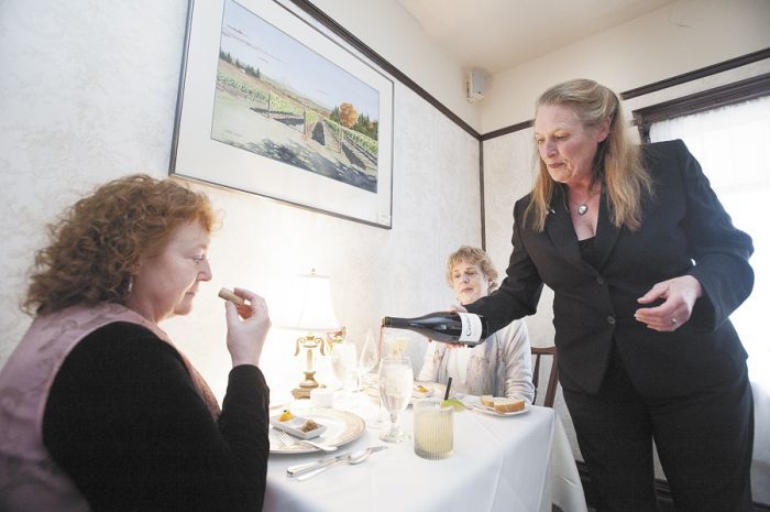 Andréa Fulton-Higgins presents and pours a bottle for dinner guests at the restaurant. She’s been in the wine industry since the ’70s. Photo by Marcus Larson.
