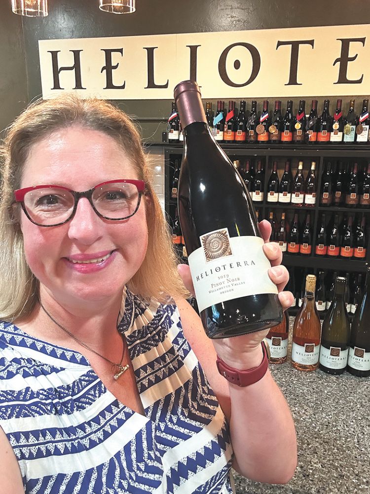 Helioterra Wines  Anne Hubatch holding a bottle of her wine. ## Photo provided by Helioterra Wines