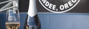 A glass of Argyle Winery sparkling wine, bottle, cap and baseball at the Hillsboro Hops&rsquo; Dugout Lounge. ## Photo provided by Argyle Winery