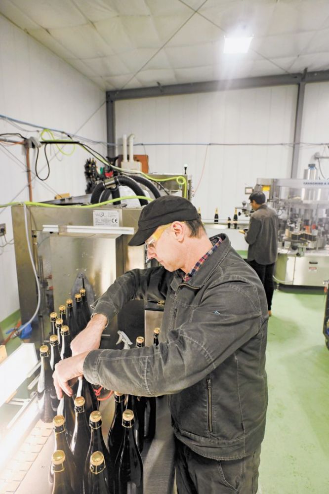 Andrew Davis, founder and owner of The Radiant Sparkling Wine Company, performing quality control measures on bottles before the foils are added.