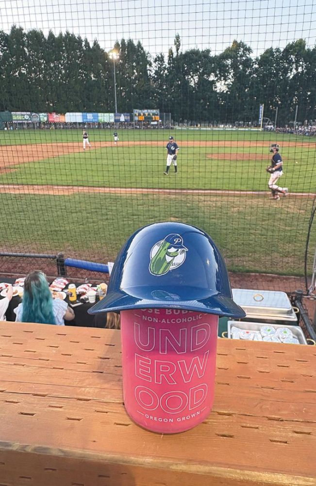 A small Portland Pickles baseball helmet on a can of Underwood wine with a game in the background. ## Photo provided by Union Wine Co.