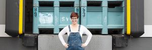 Carrie Wynkoop, founder of AVP Wine Collective, standing in front of grape bins  stacked on a loading dock. ## Photo provided by AVP Wine Collective