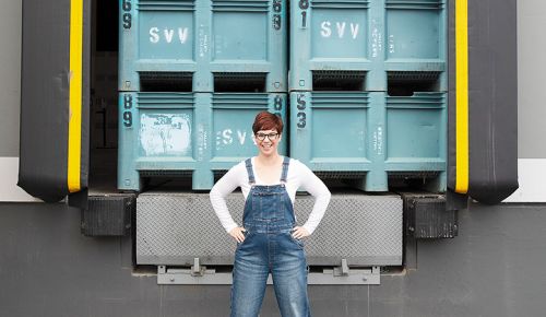 Carrie Wynkoop, founder of AVP Wine Collective, standing in front of grape bins  stacked on a loading dock. ## Photo provided by AVP Wine Collective
