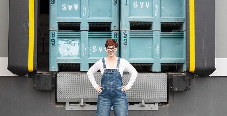 Carrie Wynkoop, founder of AVP Wine Collective, standing in front of grape bins  stacked on a loading dock. ## Photo provided by AVP Wine Collective