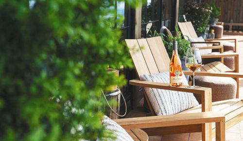 A bottle and glass of ros&eacute; sitting on the arm of an outdoor chair. ## Photo provided by Foley Family Wines