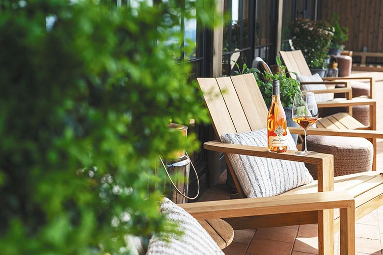 A bottle and glass of ros&eacute; sitting on the arm of an outdoor chair. ## Photo provided by Foley Family Wines