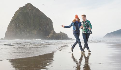 A young couple in love walk on the Oregon coast near Haystack Rock in Cannon Beach. ##Photo by Andrea Johnson.