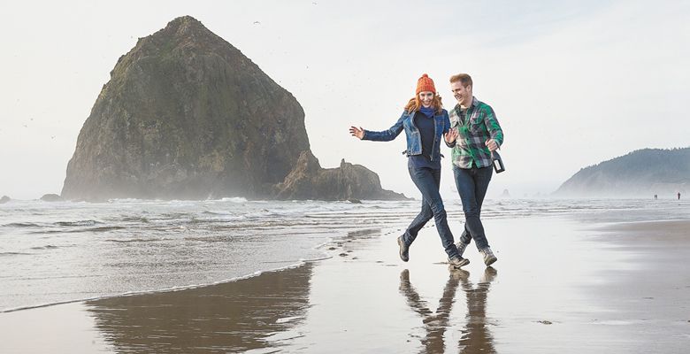 A young couple in love walk on the Oregon coast near Haystack Rock in Cannon Beach. ##Photo by Andrea Johnson.