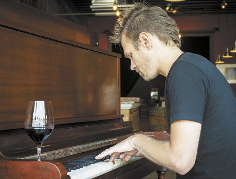 ENSO winemaker/owner Ryan Lee Sharp plays an original song at the winery’s tasting room/lounge. The turn-of-the-century piano belongs to Dave Nicolardi, an ENSO regular, who is scheduled to play at the winery every other Wednesday. Photo by Andrea Johnson.