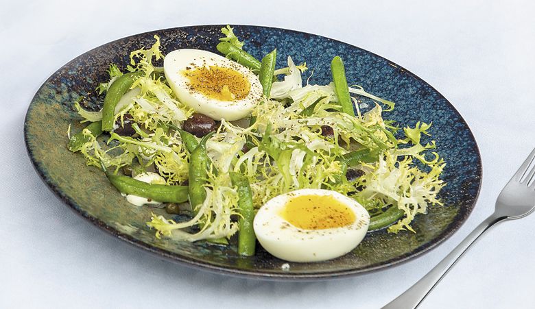 Farm fresh eggs and green beans top this frisée salad at Earth & Sea. ##Photo by Rusty Rae