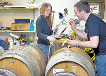 Evan and Kim Bellingar taste the progress of their wine in barrel. Photo by Janis Miglavs.