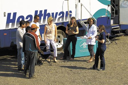 Leda Garside (white coat), and Christina Clearly, a ¡Salud! Services outreach nurse, talk to vineyard workers during a mobile clinic at Ponzi Vineyards’ winery. Maria (left) and Luisa Ponzi help with the check in.