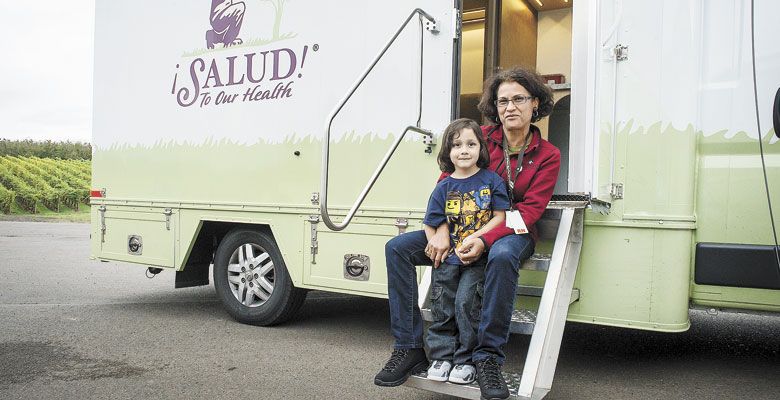 ¡Salud! Manager Leda Garside pauses during a busy Wellness Clinic with one of the younger beneficiaries of the program. They sit on the steps of the new mobile clinic nicknamed “Lady Bug.” ##Photo by Andrea Johnson