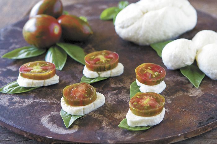 Whether accompanied by DIY cheese or cheese from the market, savor summer on a plate with these super simple Caprese Stacks. Slice vine-ripe plum tomatoes, and stack with slices of mozzarella, fresh basil and a sprinkle of salt. Drizzle with olive oil or balsamic vinegar for a super simple stacked salad Photo by Christine Hyatt
