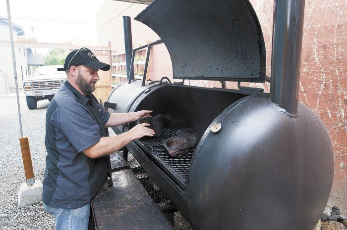 Loal Stahlnecker rotates beef brisket in Storrs’ smoker located behind the restaurant.Photo by Marcus Larson