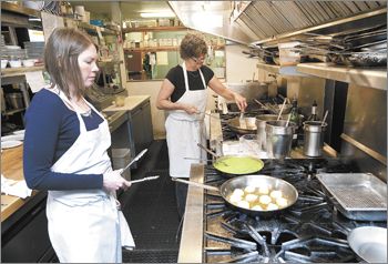 Tina’s co-owner Tina Bergen, background,
and chef Abby McManigle prepare the scallop entrée for the Dundee restaurant’s 20th
anniversary media luncheon.