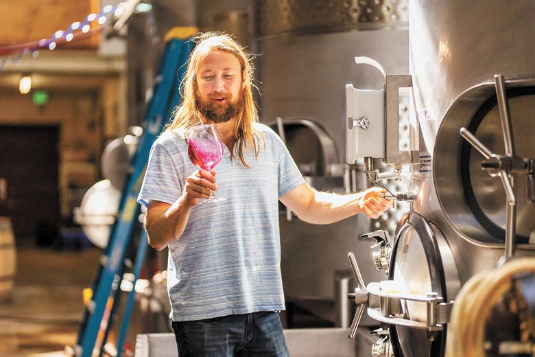 Winemaker Alex Fullerton tasting wine from a tank. ##Photo by Josh Chang