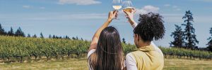 Two women raising their glasses as they look out at a vineyard on a summer day. ## Photo by Gregory Woodman