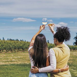 Two women raising their glasses as they look out at a vineyard on a summer day. ## Photo by Gregory Woodman