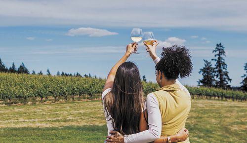 Two women raising their glasses as they look out at a vineyard on a summer day. ## Photo by Gregory Woodman