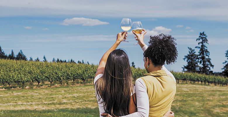Two women raising their glasses as they look out at a vineyard on a summer day. ## Photo by Gregory Woodman