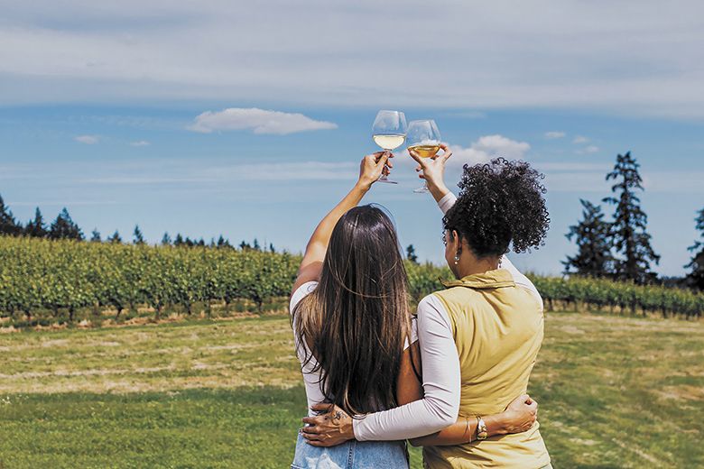 Two women raising their glasses as they look out at a vineyard on a summer day. ## Photo by Gregory Woodman