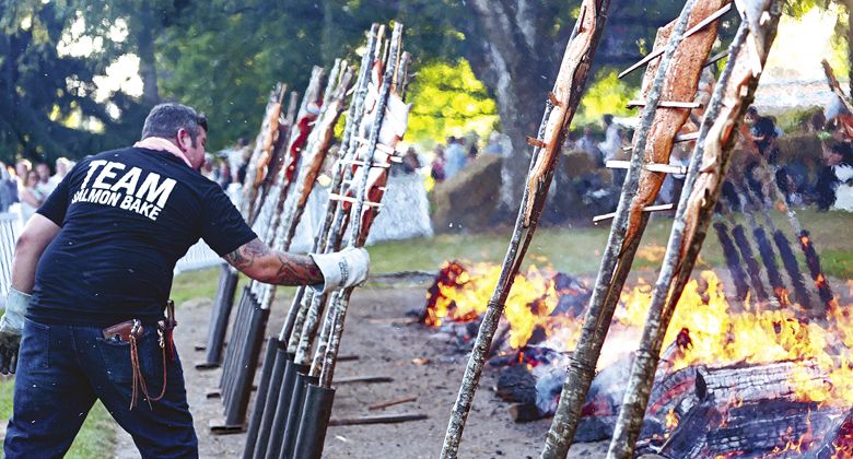 A volunteer positions the salmon in
the burning embers during the popular Salmon Bake. ##Photo by Carolyn Wells-Kramer