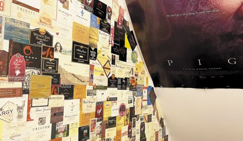 The staircase to the wine cellar
reveals bottles “killed” at The Joel Palmer
House in Dayton. The poster hanging above
shows “Pig,” a recent thriller of which the
Czaneckis proudly consulted. ##Photo by Hilary Berg