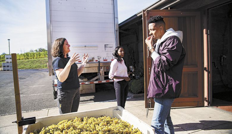 Hennen offers McCollum a taste of the harvest. ##Photo by Justin Tucker / Nine Eighty Four