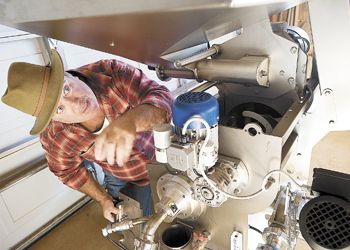 PHOTO: Olive farmer David Lawrence
checks on the olive press at Oregon Olives
east of Amity. Photo by Marcus Larson.