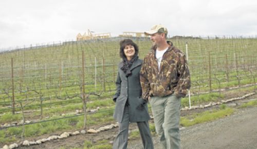 Kriselle Cellars sales manager, Nora Lancaster, and operations manager, Jay Crowl, walk among the vines at the winery’s estate vineyard. the 3,000-square-foot tasting room is under construction at the top of the hill.