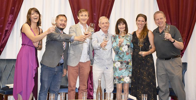 Oregon Wine Competition judges toast the winemakers at the public forum (from left): Ashley Myers, OWC
Moderator; Andrey Ivanov, MS; Maximillian Kast, MS; Peter Marks, MW; Ellen Landis, CS, CSW; Ashley Hausman, MW;
Bruce Nicholson, OWC Chair. Missing, Deborah Parker Wong, DWSET. ##Photo by Maureen Battistella