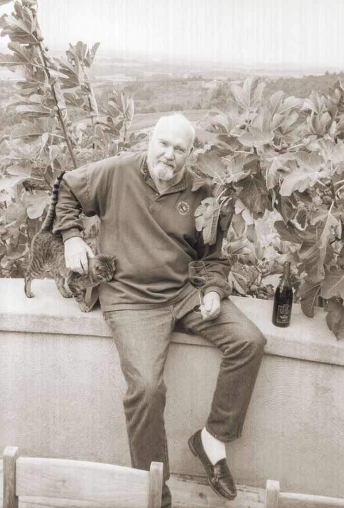 Dick Erath poses for a picture with a cat and a bottle of wine.##Jereld R. Nicholson Library, Linfield university, ¡Salud! Program