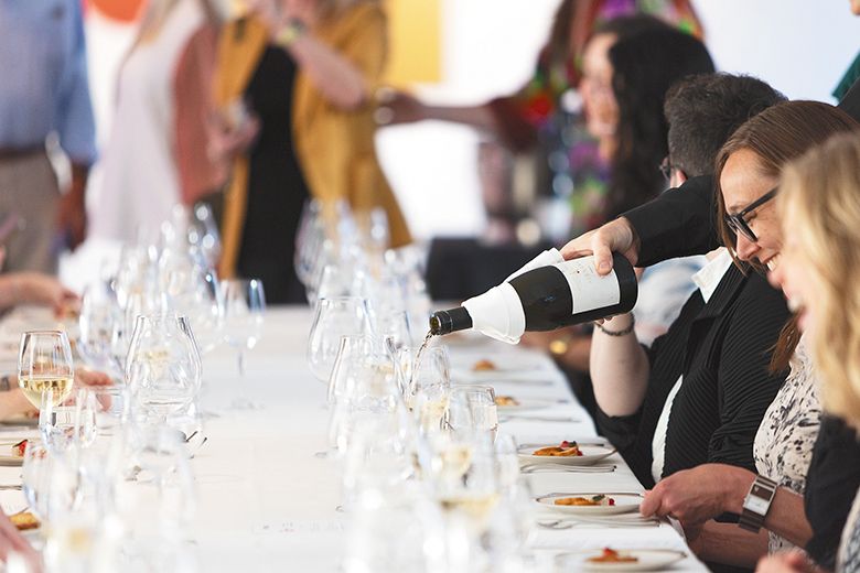 Glasses being filled with white wine while diners are seated at the communal tables. ## Photo By Kitta Bodmer