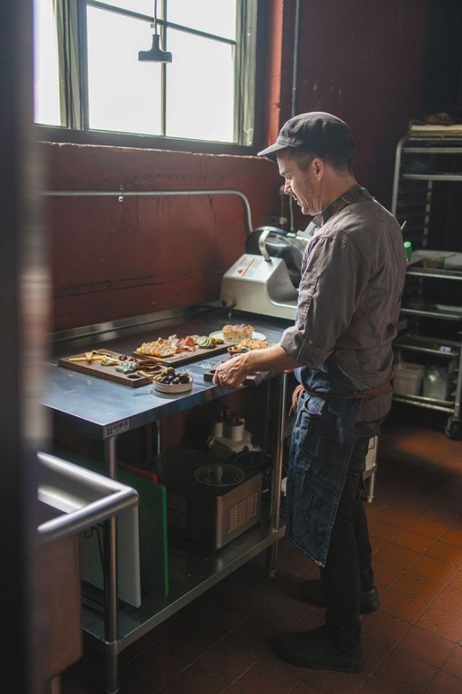 Chef Joey Gibson preparing cheese and charcuterie boards in Parallel’s kitchen. ## Photo by Josh Chang/Foundry 503