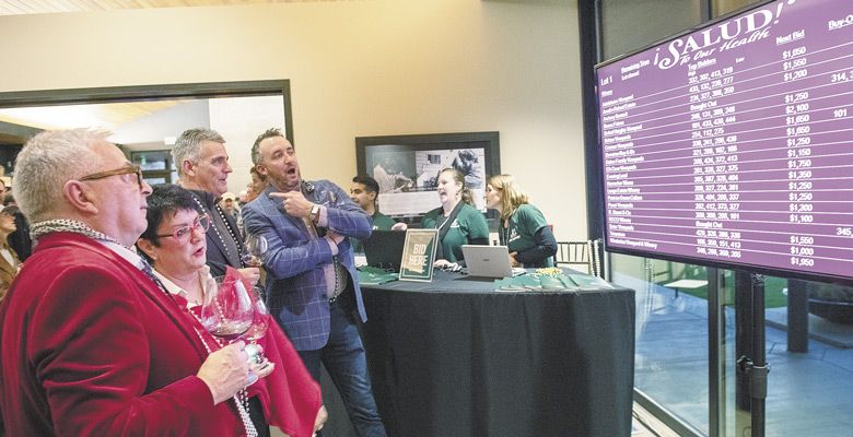 Guests at Friday’s Big Board Auction keep a keen eye on the screen as bids increase throughout the evening for exclusive wines made for ¡Salud!. ##Photo by Andrea Johnson